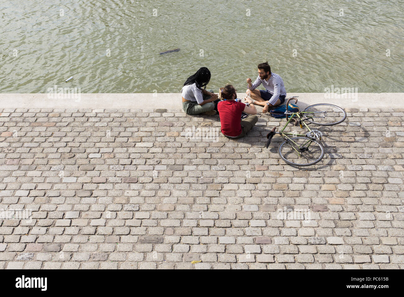 Freunde in der Nähe von Wasser - drei Freunde von oben sitzen und plaudern auf einem Kanal Bank gesehen. Stockfoto