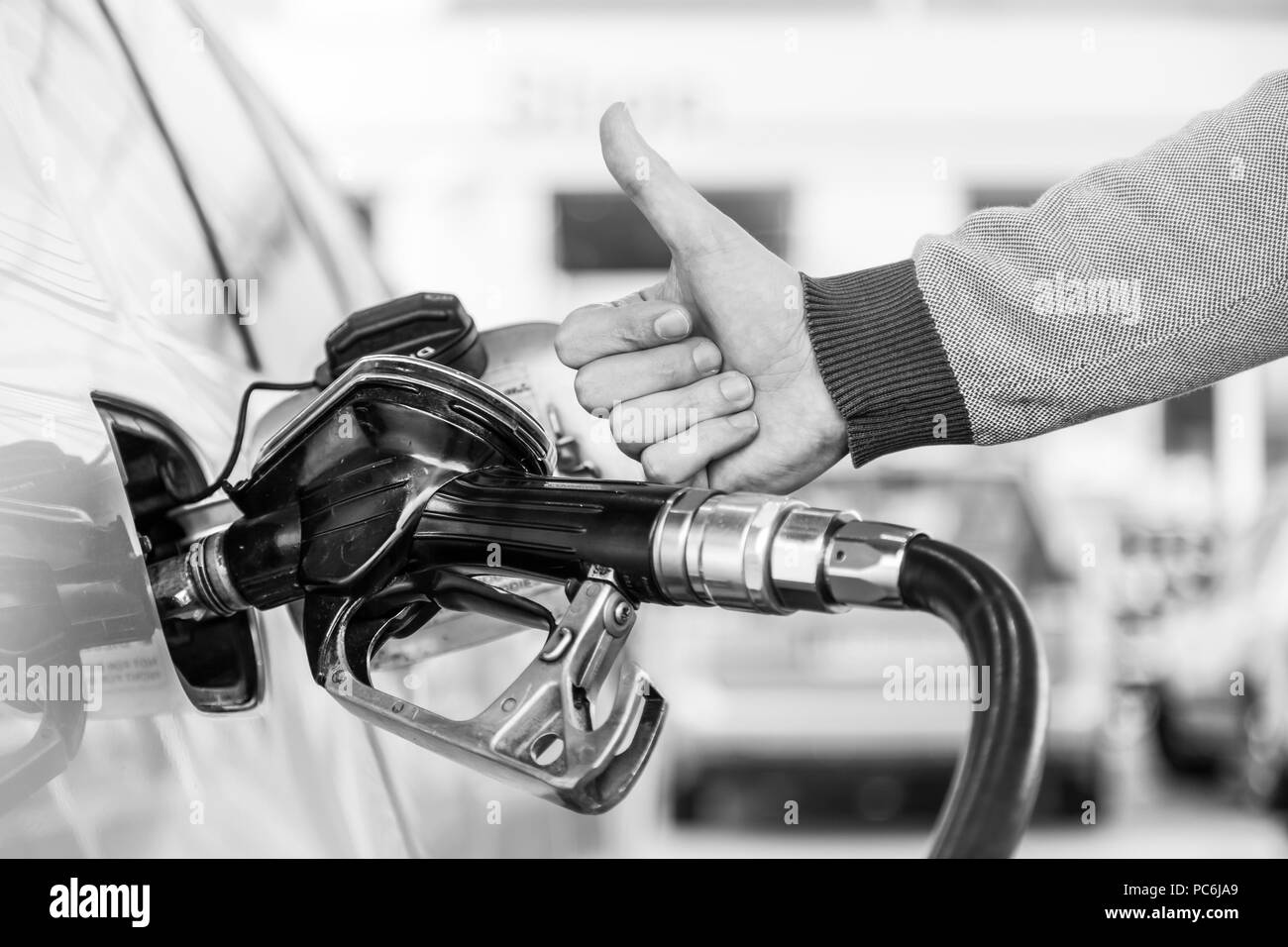 Benzin oder Benzin in ein Kraftfahrzeug Auto gepumpt. Nahaufnahme des Menschen, zeigt Daumen oben Geste, Pumpen Benzin Kraftstoff im Auto an Tankstelle. Stockfoto