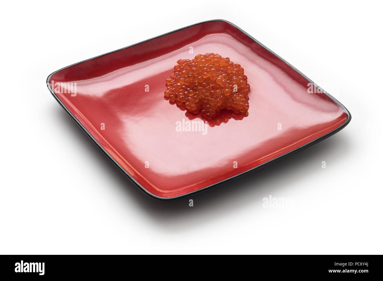 Roter Lachskaviar auf ein rotes Quadrat Platte, isoliert auf weißem Stockfoto