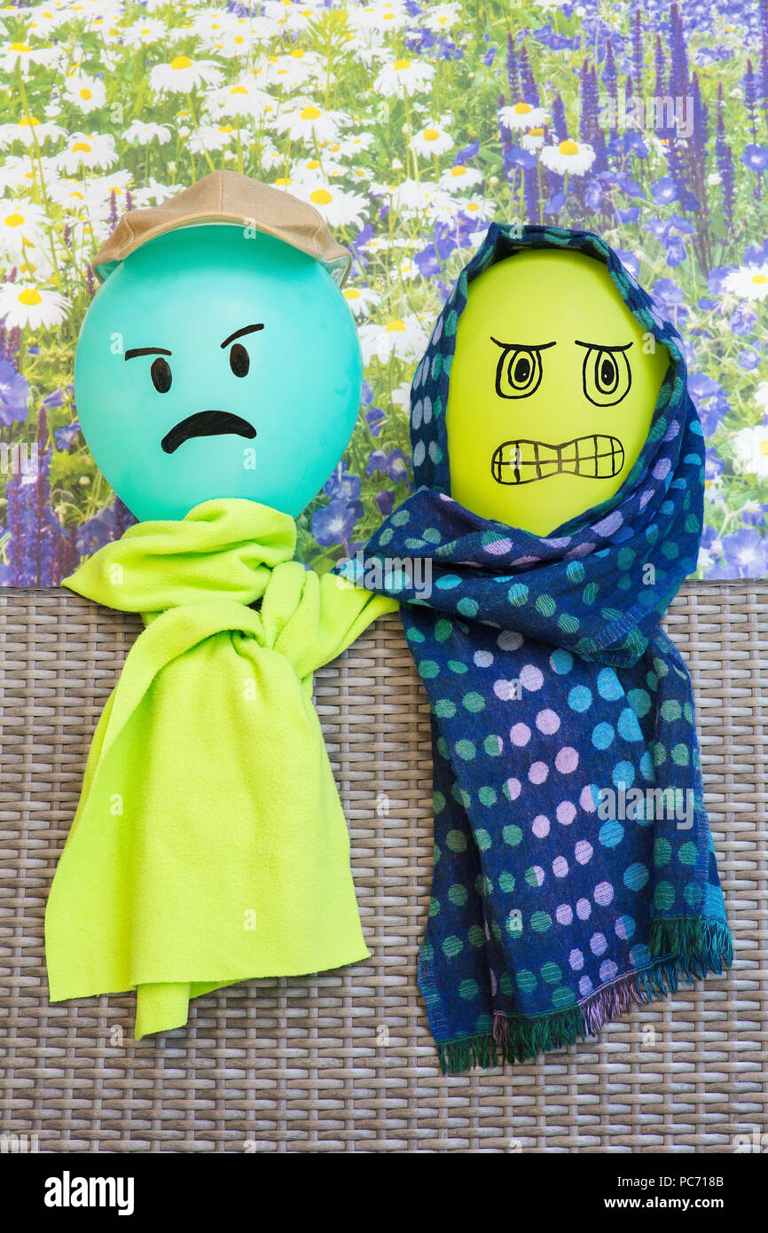 Zwei Ballons mit verärgerten Gesichtsausdruck tragen grüne Schals Stockfoto