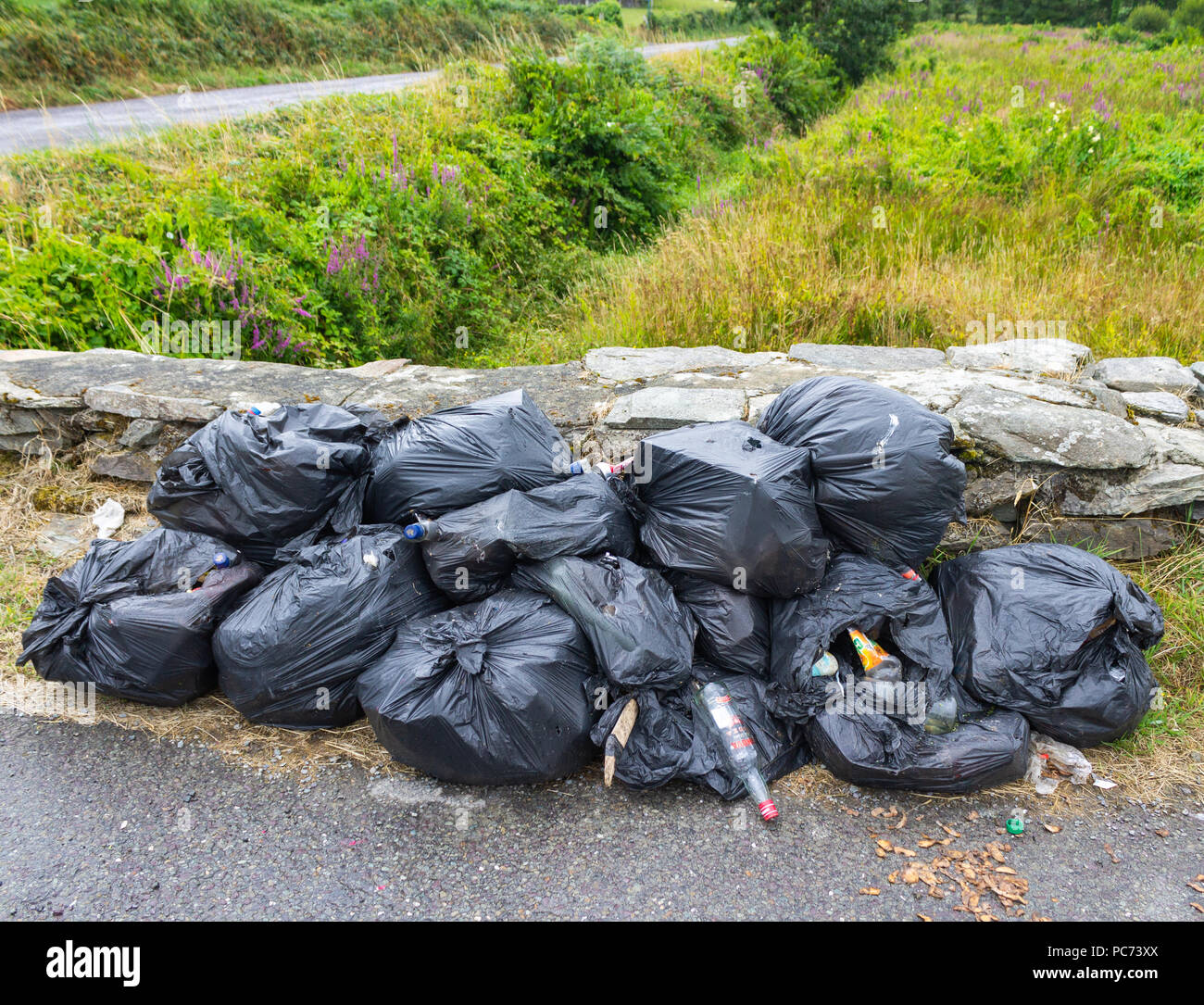 Kunststoff Abfallsäcke gefüllt mit faulendem Abfall entleert auf den Straßenrand. Stockfoto