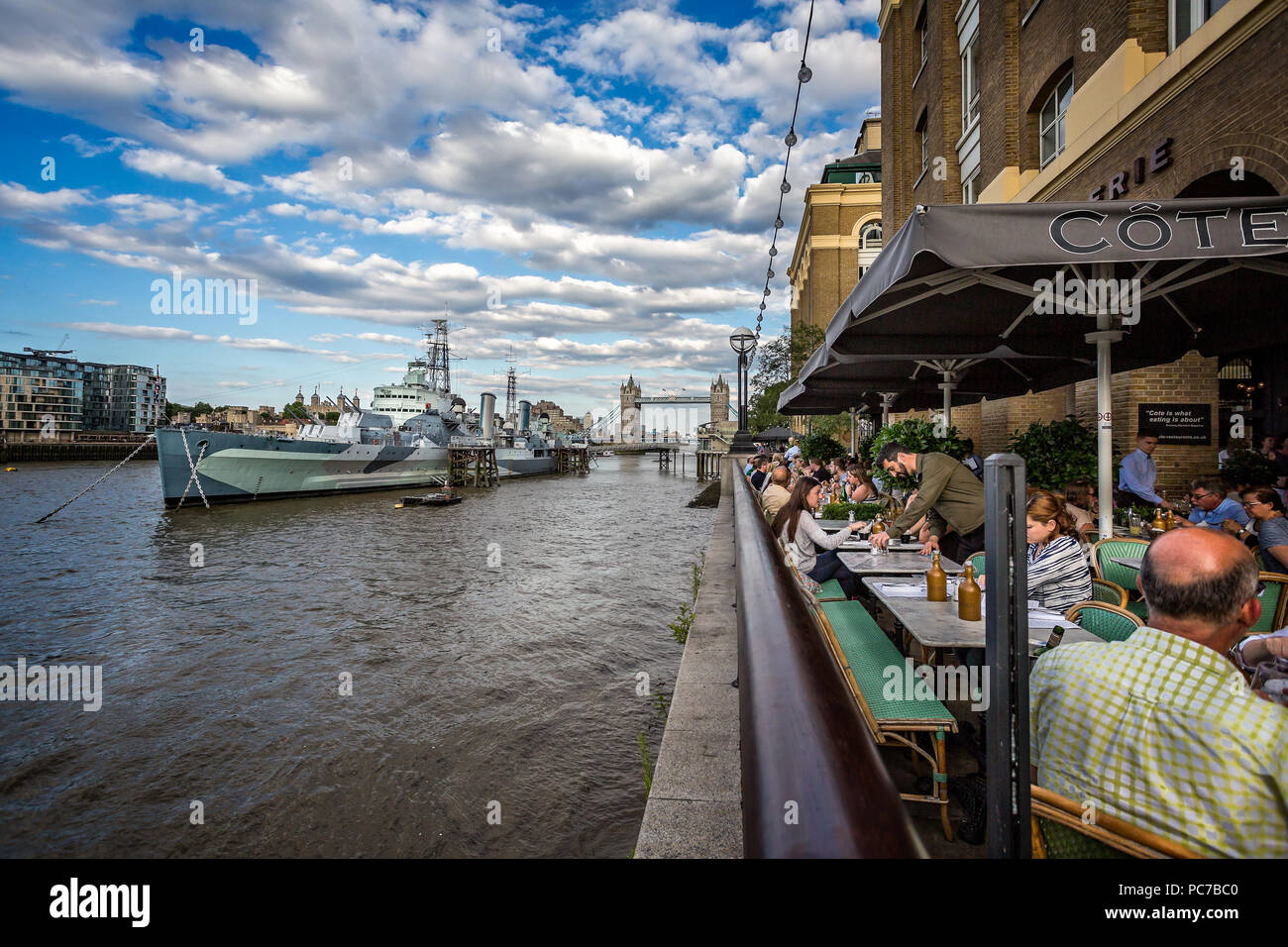 Diners am Südufer der Themse, die Tower Bridge & HMS Belfast in London, Großbritannien, am 8. Juli 2017 Stockfoto