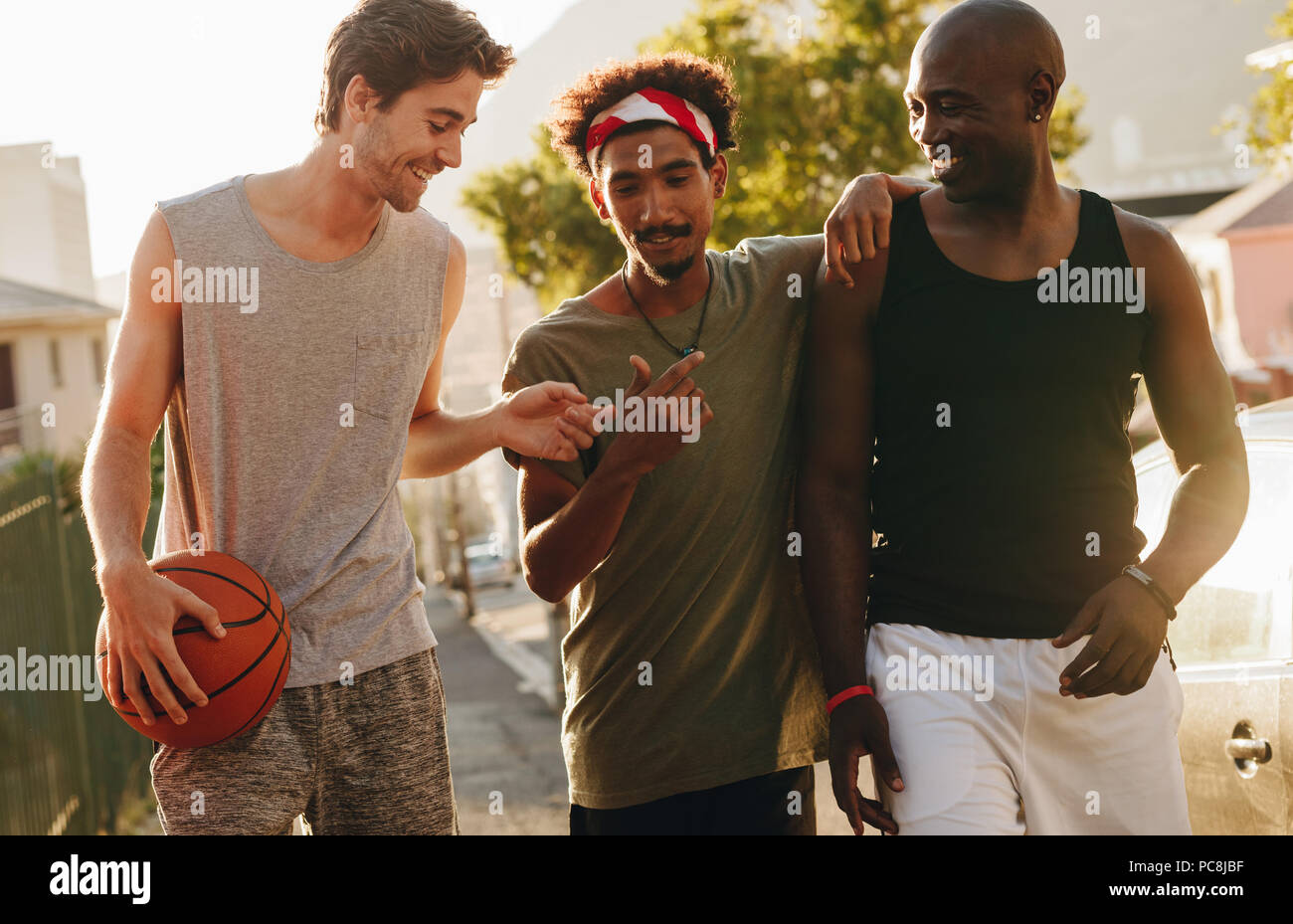 Drei basketball Männer auf der Straße reden und Spaß haben. Männer zu Fuß zurück nach einem Spiel der Basketball. Stockfoto