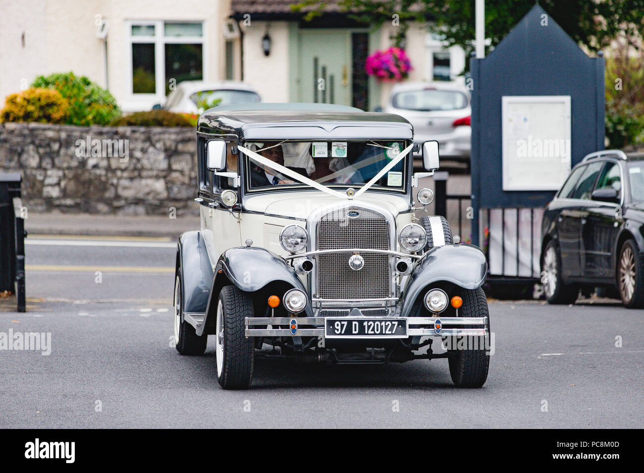 Braut, die Ankunft der Kirche an ihrem Hochzeitstag in einem vintage Thomasburg Limousine. Stockfoto