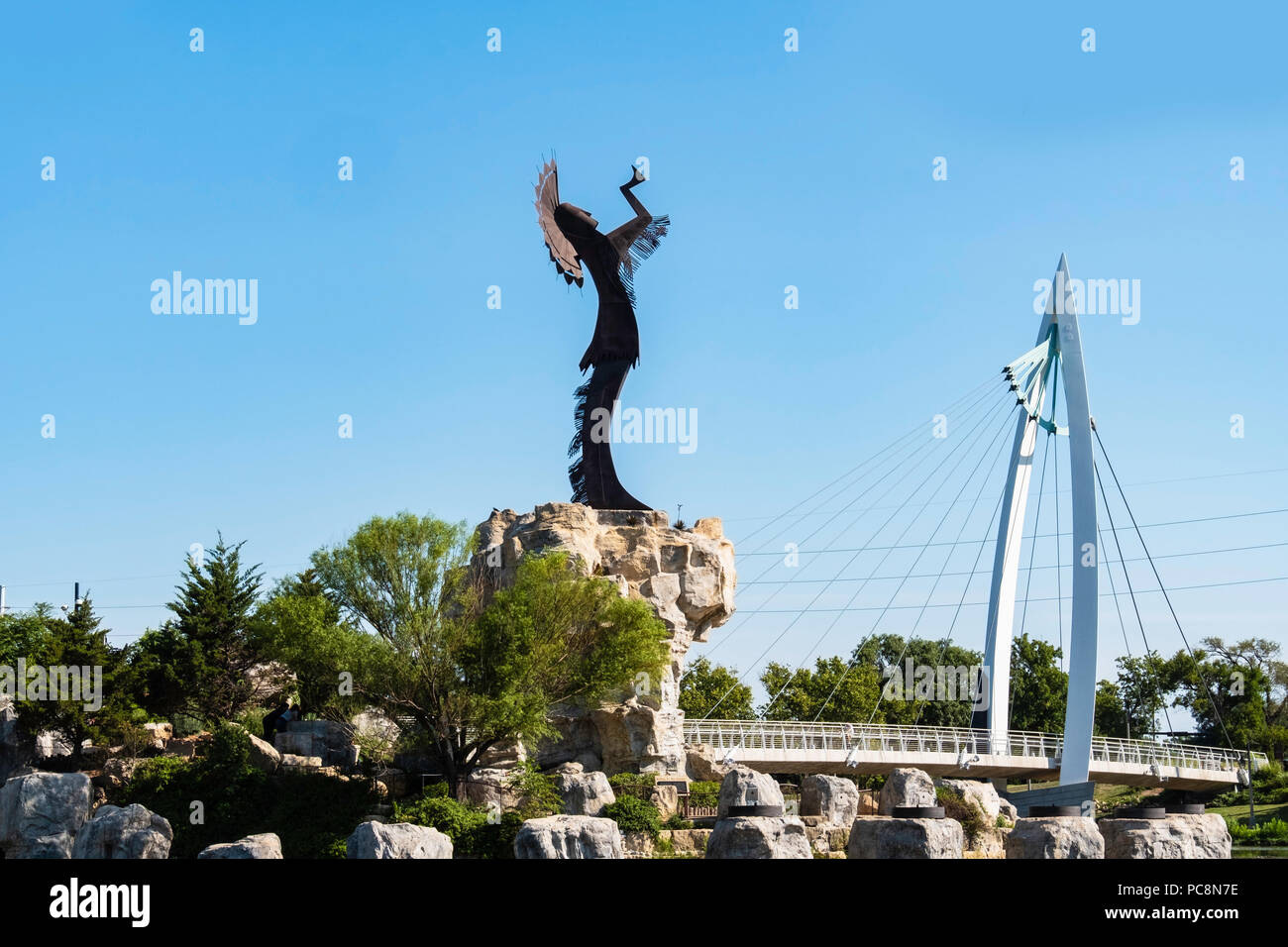 Hüter der Plains, eine stählerne Skulptur von Blackbear Bosin. Wichita, Kansas, USA. Sichtbar ist ein Fußgänger-Hängebrücke. Stockfoto