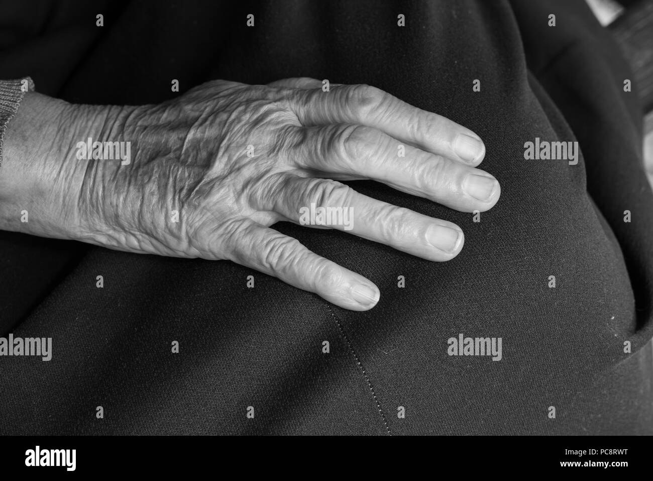 Die Hand einer alten Frau auf ihrem Schoß - Schwarz und Weiß Stockfoto