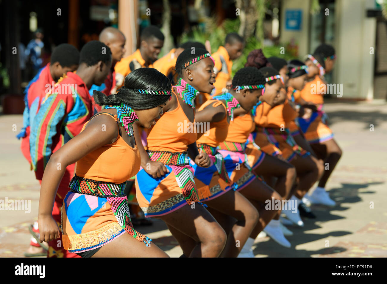 Young Zulu Männer und Frauen in bunten kulturellen Kleid tanzen und singen bei Open-air-Performance, Durban, Südafrika Stockfoto