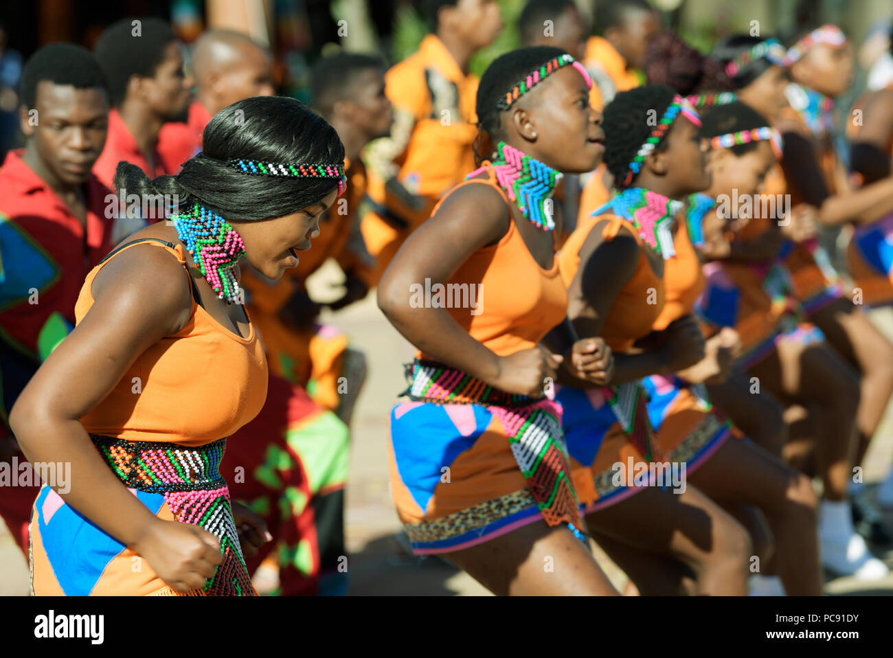 Junge Frauen und Männer von Street Performer Gruppe der traditionellen Zulu Lieder in bunten Kleid bei uShaka Marine World, Durban Stockfoto