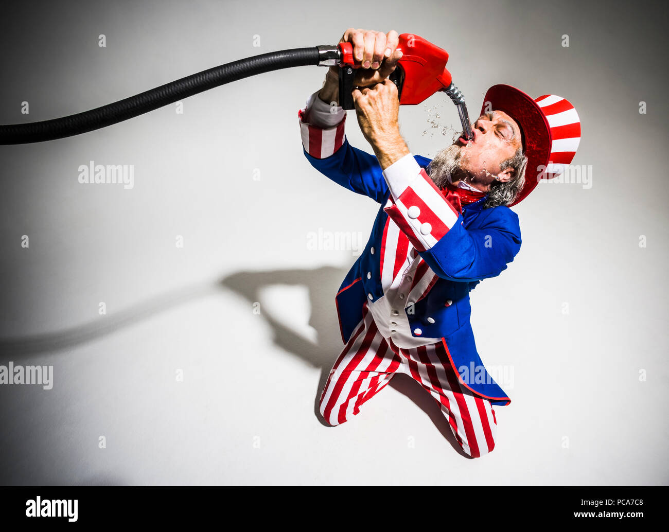 Uncle Sam saugen Benzin aus einem Gas Pumpe Düse. Zu Öl-/fossilen Brennstoffen abhängig. Stockfoto