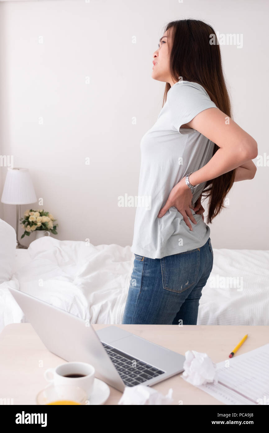 Asiatische Frau Freiberufler Rückenschmerzen vom lange Zeit zu Hause arbeiten. Arbeit zu Hause Konzept Stockfoto