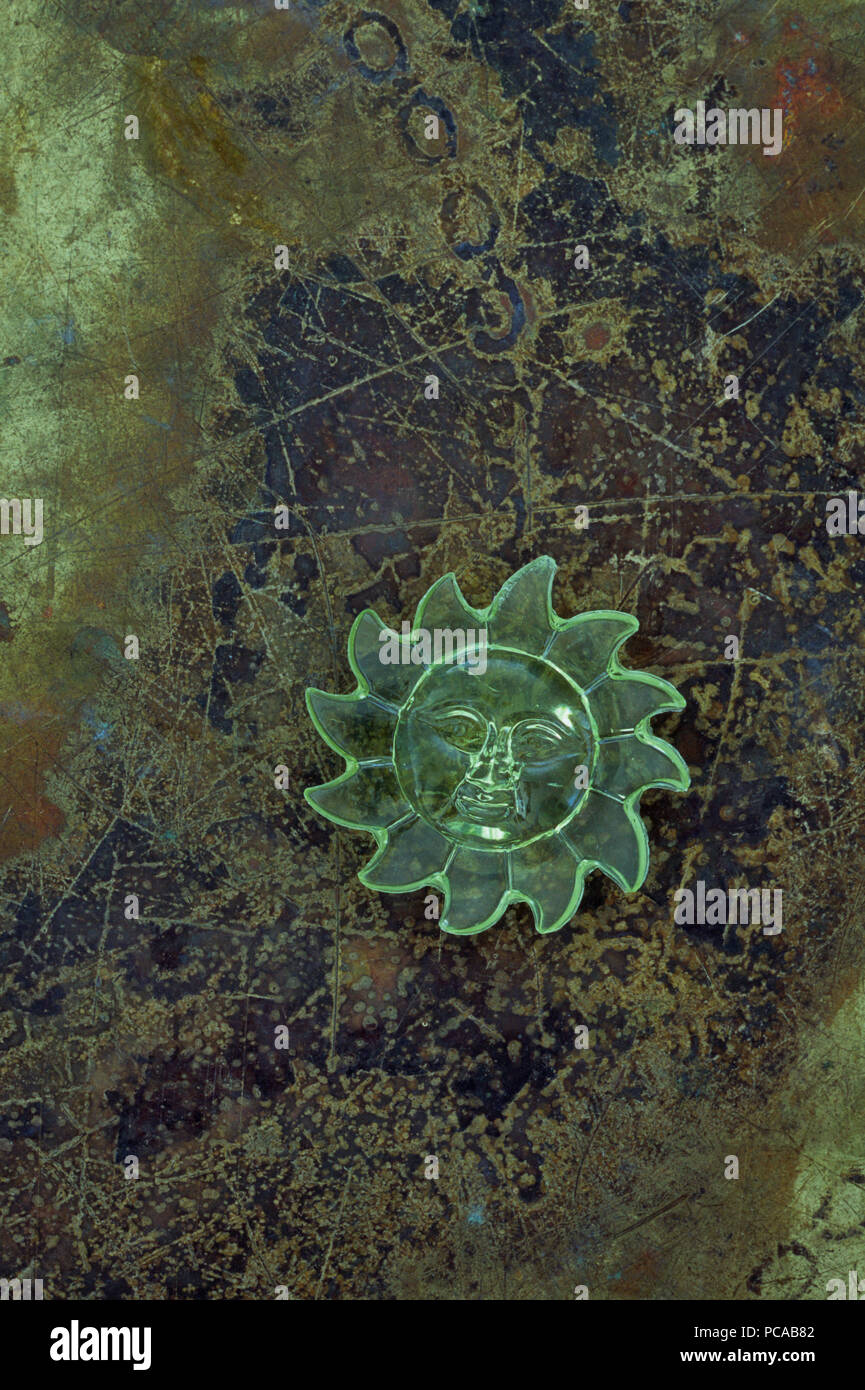 Grün transparent Kunststoff Modell der lächelnden Sonne liegen auf getrübt Messing Stockfoto