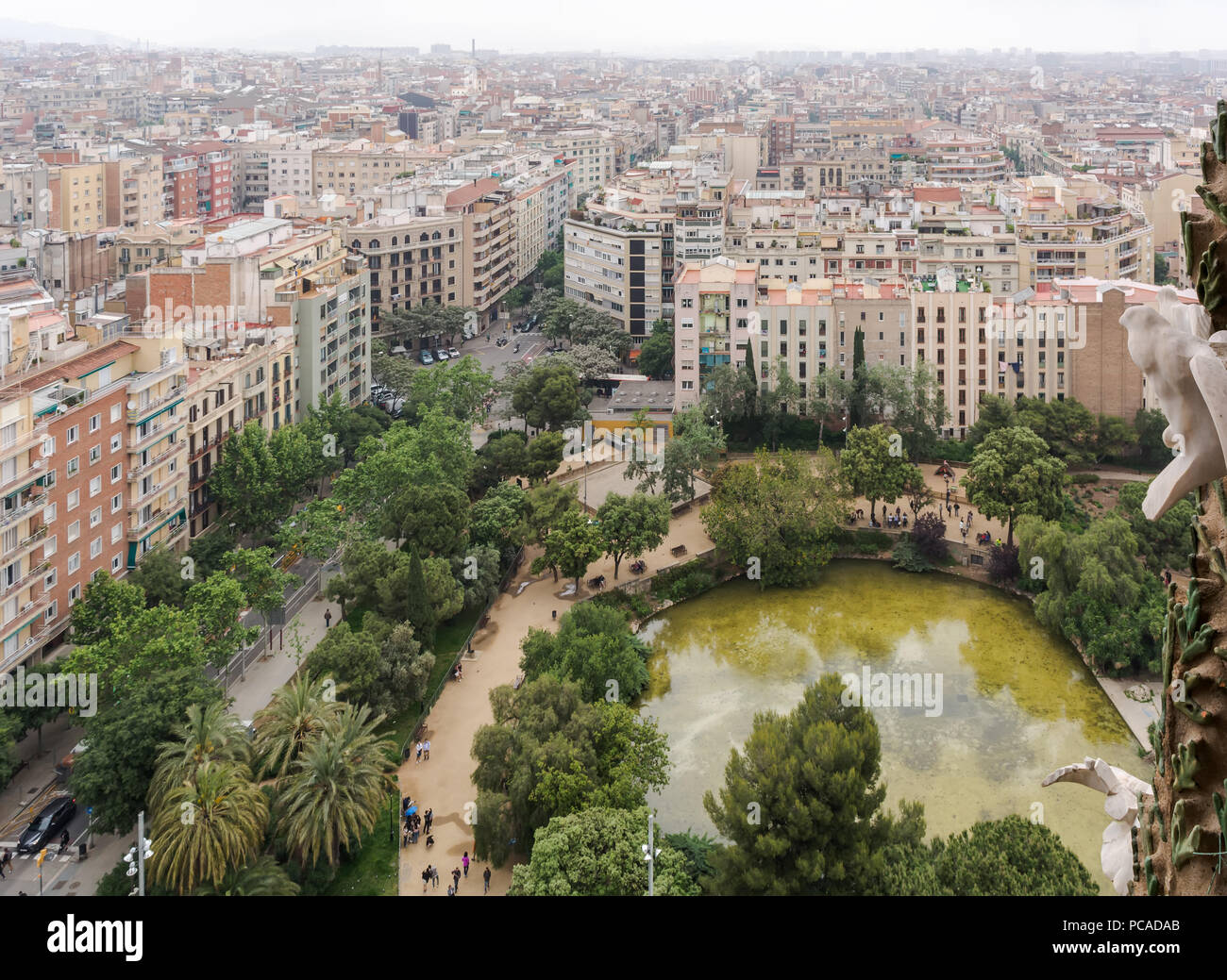 Blick auf Barcelona von der Sagrada Familia, der mit dem grünen Teich auf der Plaza de Gaudi (Gaudi) vor der Kirche und die Bäume Stockfoto