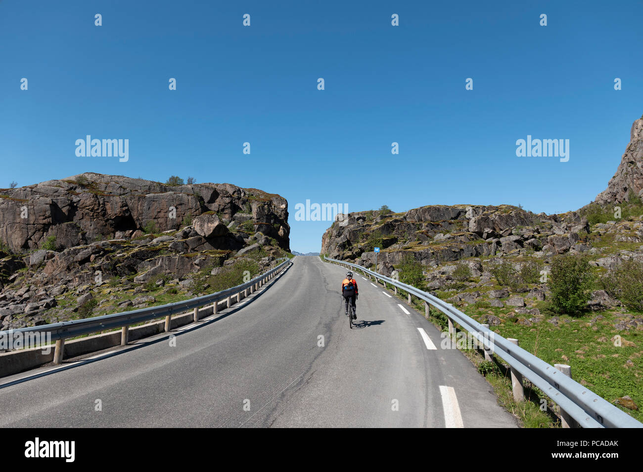 Weibliche Straße Radfahrer auf der Straße zu Henningsvær, Lofoten, Norwegen. Stockfoto