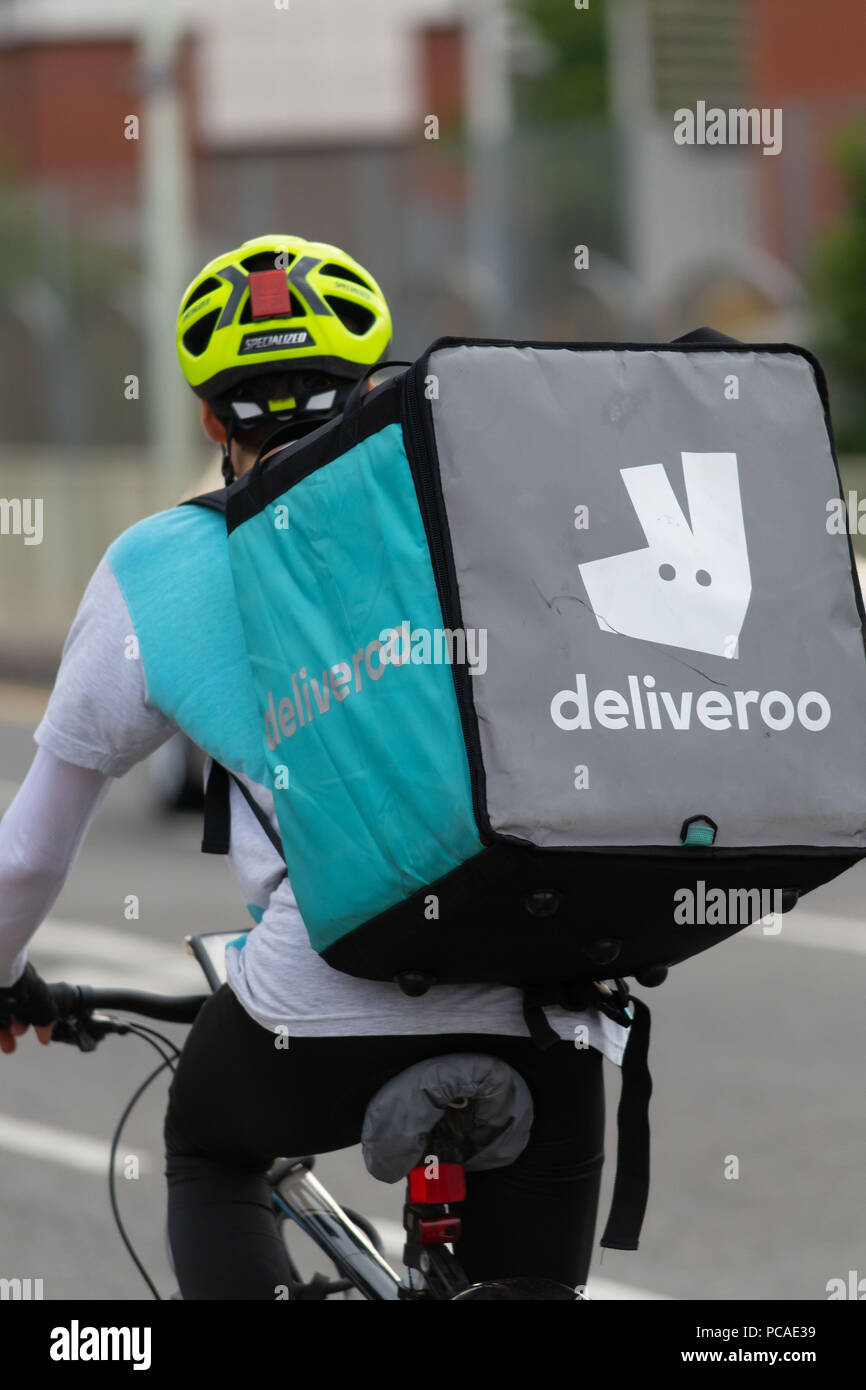 Eine Deliveroo fast food Anlieferung Treiber auf einem Fahrrad in Cardiff, Wales, UK gesehen. Stockfoto