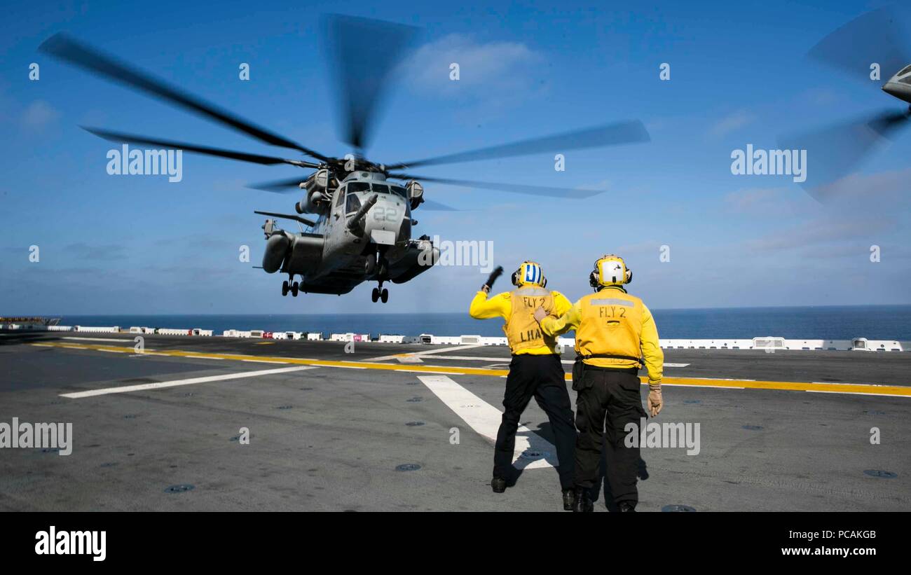 Pazifik - U.S. Navy Sailors guide Ein CH-53E Super Stallion von Marine Medium Tiltrotor Squadron 166 verstärkt, 13 Marine Expeditionary Unit (MEU), während einer planmäßigen Einsatz der Essex Amphibious Ready Group (ARG) und die 13. MEU, 11. Juli 2018. Das Essex ARG/MEU Team ist eine starke, flexiblen, reaktionsschnellen und gleichbleibende Kraft in der Lage, Manöver Kriegsführung in allen Domänen; es ist ausgestattet und skalierbar auf jede Krise von der humanitären Hilfe und Katastrophenhilfe zu Blindbewerbungen zu reagieren. (U.S. Marine Corps Foto von Cpl. A. J. van Fredenberg) Stockfoto