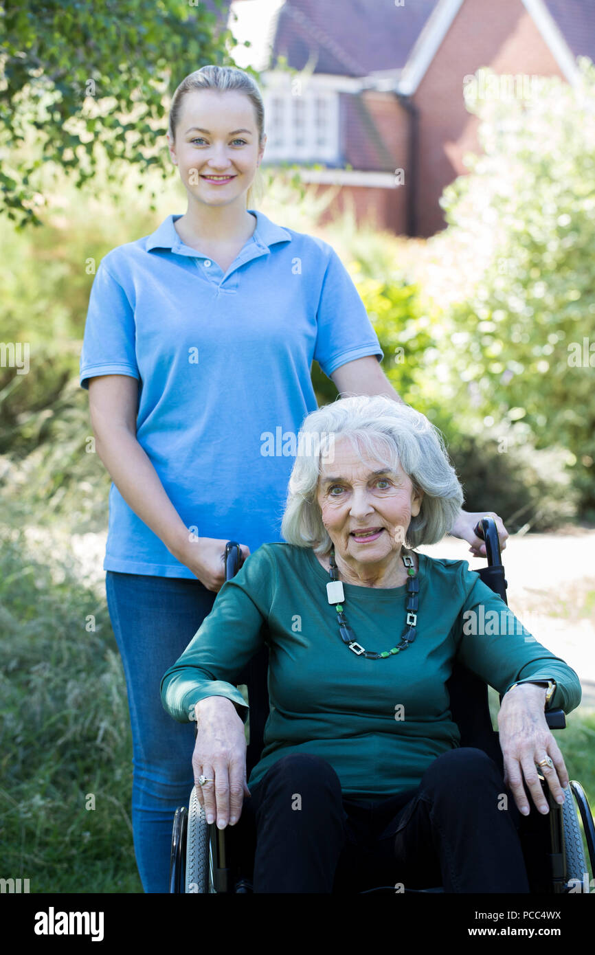 Portrait von pflegeperson Drücken ältere Frau im Rollstuhl außerhalb Home Stockfoto
