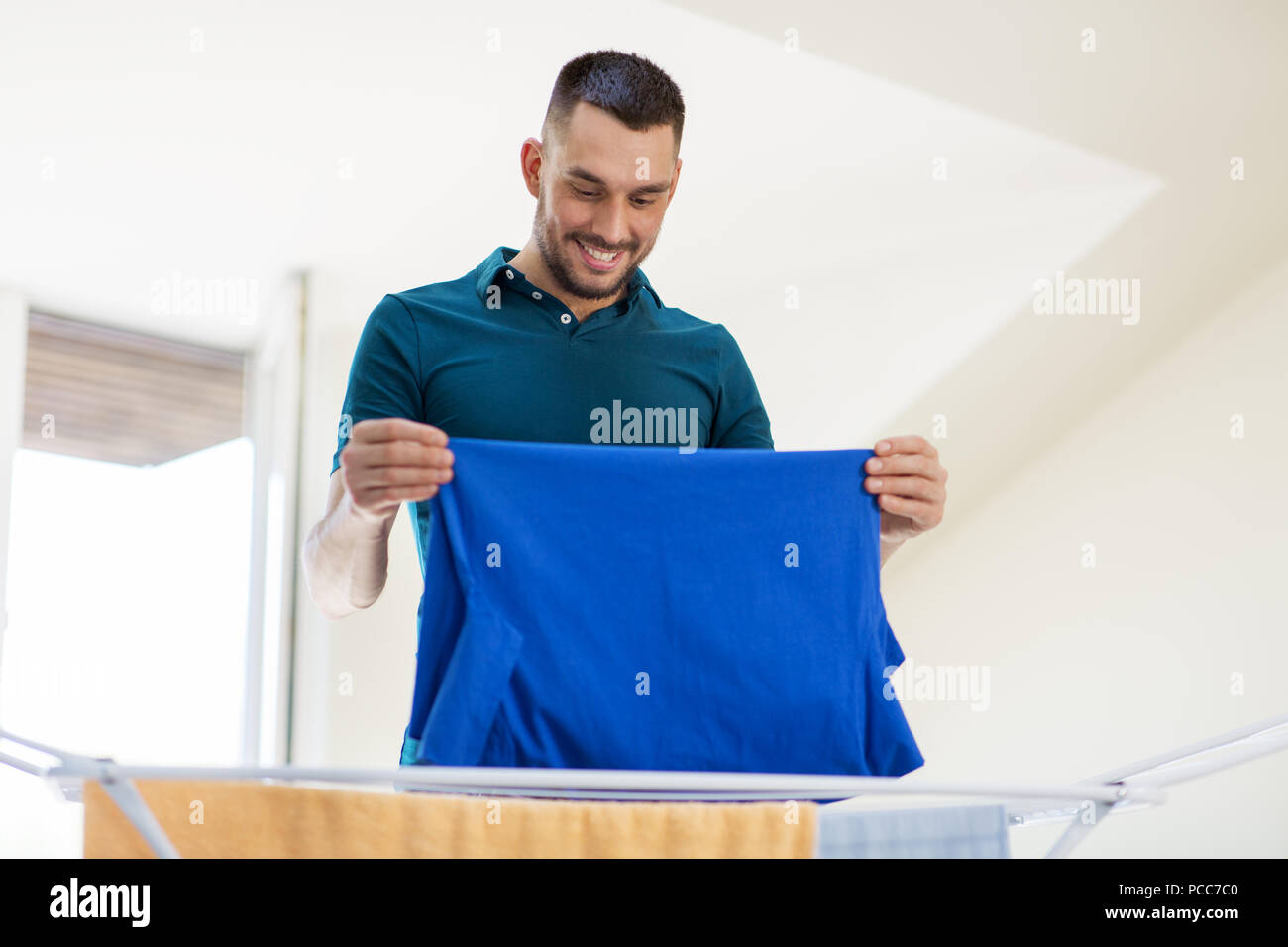 Lächelnder Mann mit Waschmaschine und Wäschetrockner zu Hause Stockfoto