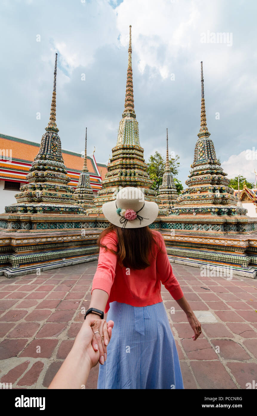 Porträt der schönen Asiatin führt Ihr Partner von Hand zu den berühmten Wat Pho. Wat Pho ist eine buddhistische Tempelanlage in Bangkok, Thailand Stockfoto