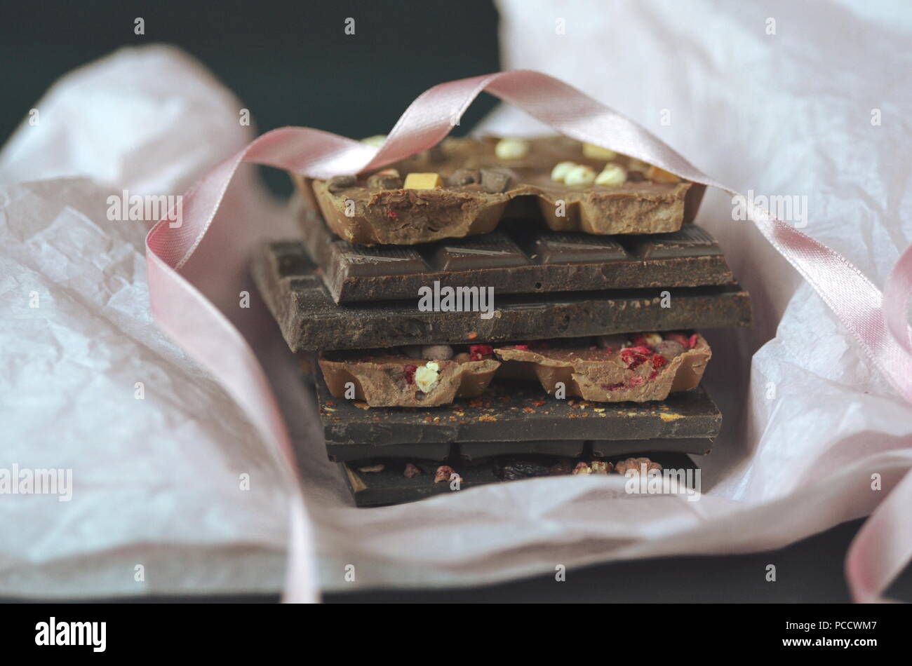 Ein Geschenk Pack von artisan handgemachte Schokolade. Bars Schokolade mit getrockneten Früchten auf dunklem Hintergrund, der Nähe zu sehen. Stockfoto