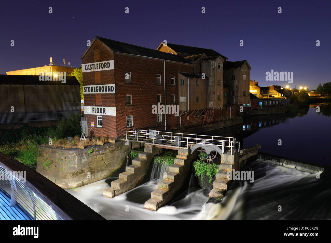 Castleford Stoneground Mühle in der Nacht neben der Millennium Bridge, die sich über den Fluss Aire Stockfoto