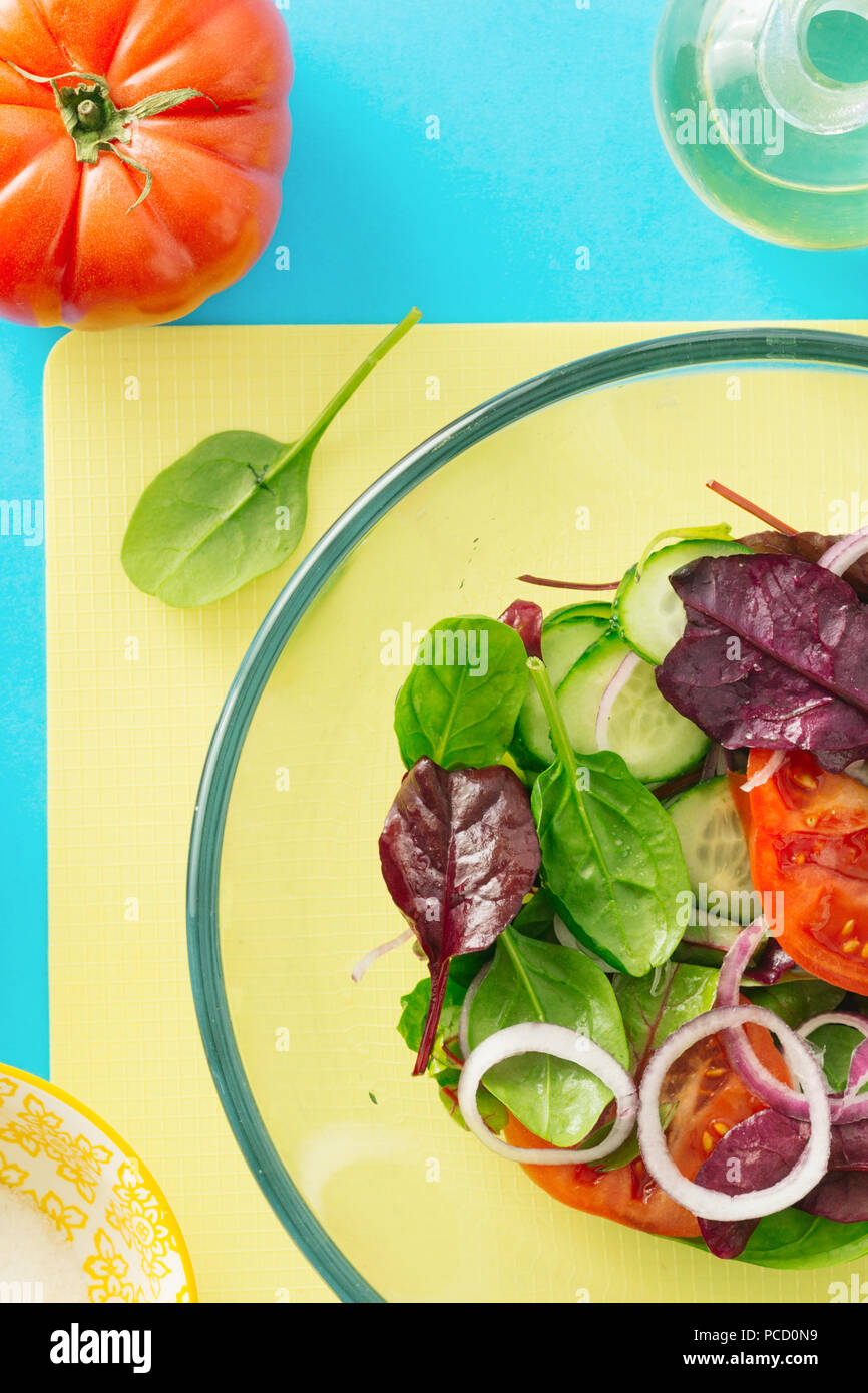 Sommer Salat in Glasschale auf blauem Hintergrund, Ansicht von oben. Gesunde Ernährung Konzept. Ernährung Lebensmittel Stockfoto