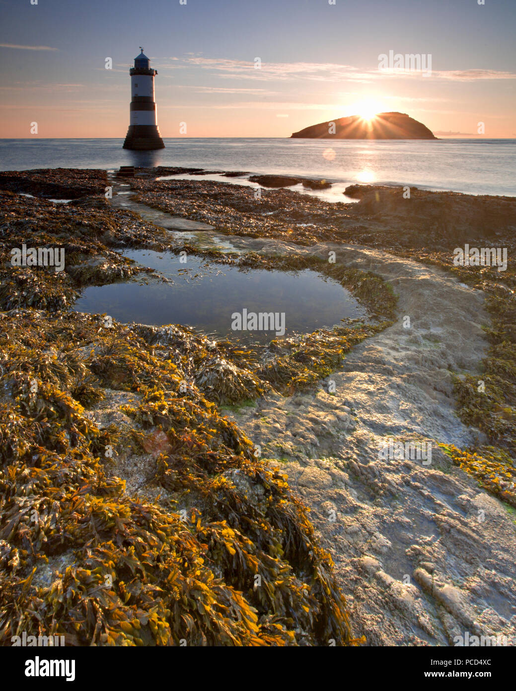 Leuchtturm am Penmon Punkt bei Sonnenaufgang, Anglesey, Nordwales, mit Puffin Insel im Hintergrund Stockfoto