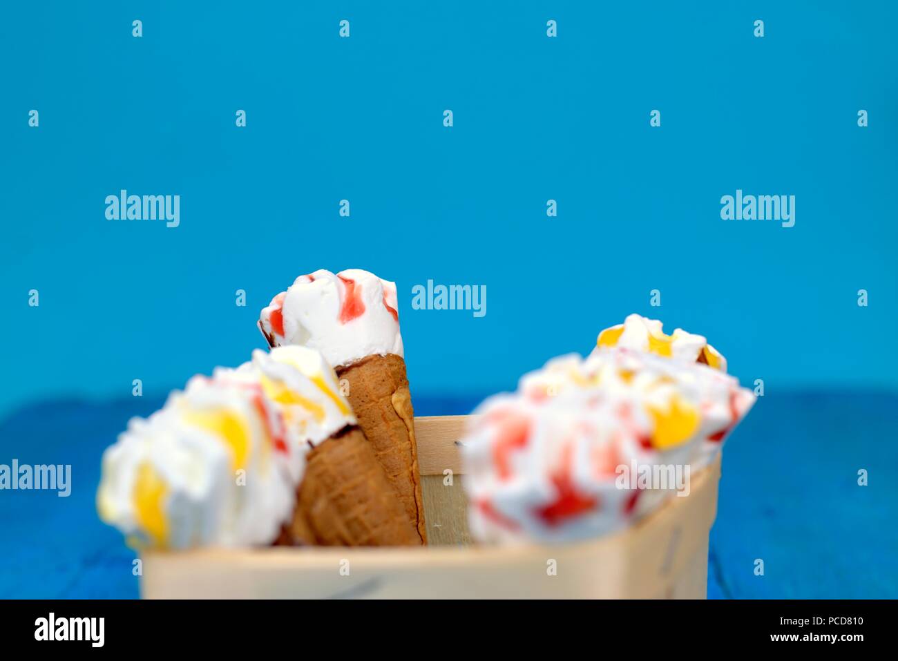 Süße frische Nachtisch, Kälte und Eis Konzept: eine Holzkiste mit Eistüten auf blauem Hintergrund. Stockfoto