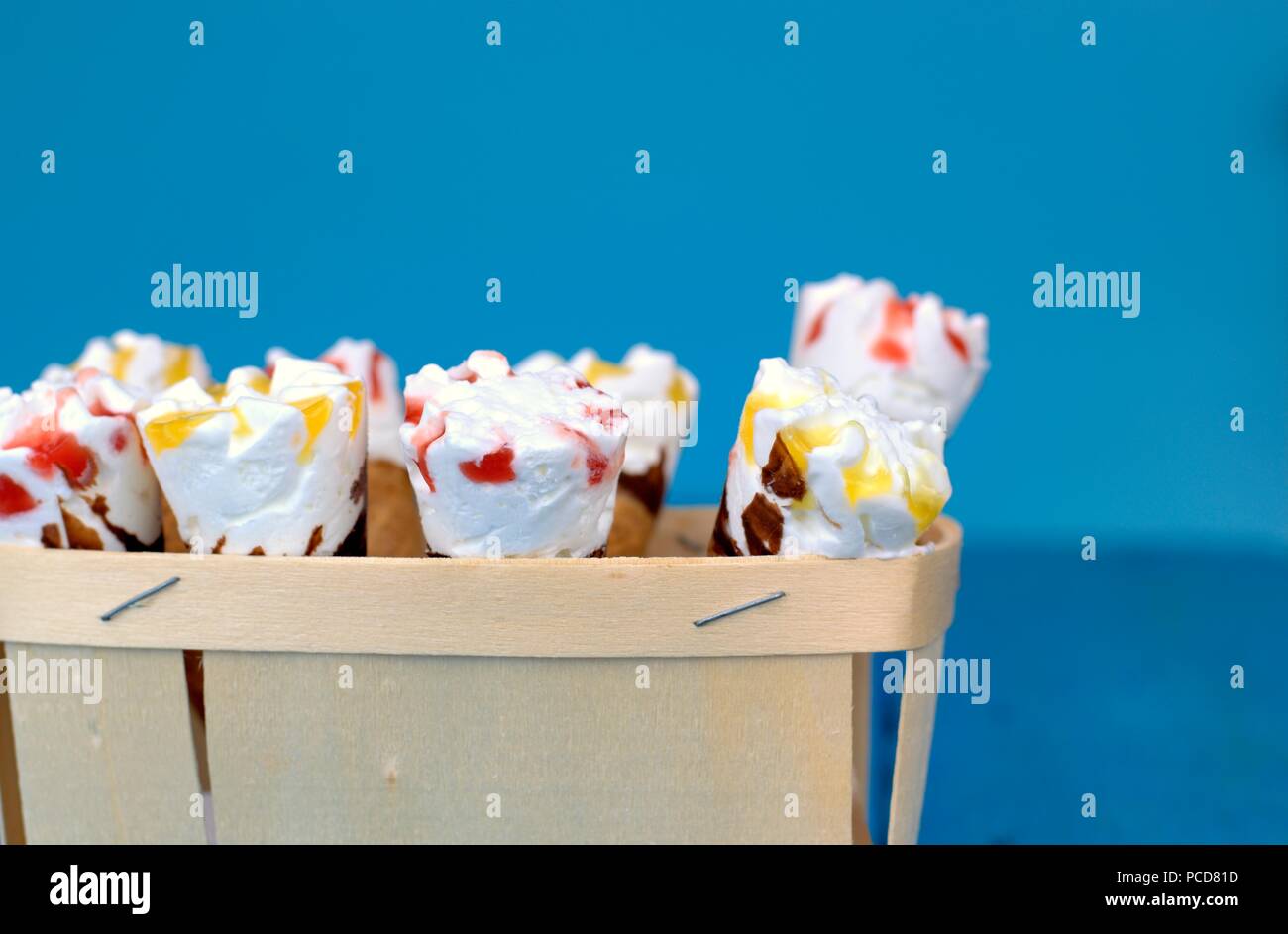 Süße frische Nachtisch, Kälte und Eis Konzept: eine Holzkiste mit Eistüten auf blauem Hintergrund. Stockfoto