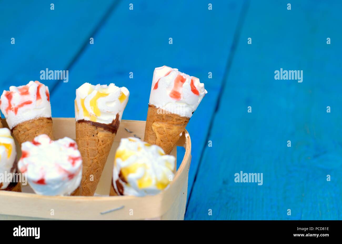 Süße frische Nachtisch, Kälte und Eis Konzept: eine Holzkiste mit Eistüten auf blauem Hintergrund. Stockfoto