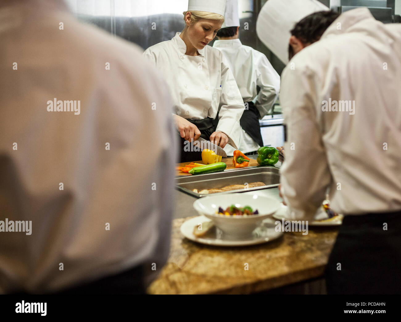 Ein Blick durch die Küche Mitarbeiter einer Köchin Schneiden von Gemüse. Stockfoto