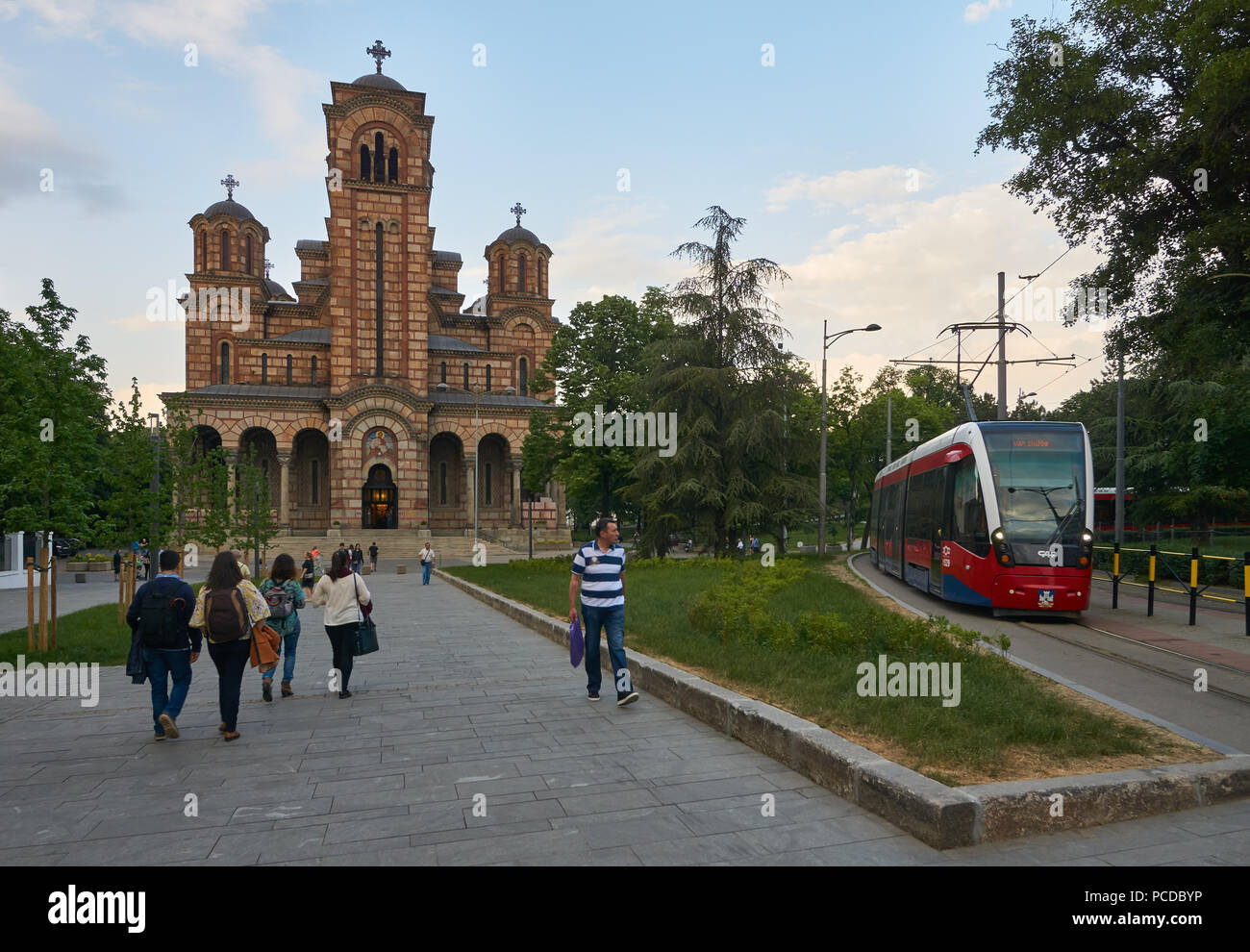 Belgrad, Serbien - Mai 04, 2018: Abendlicher Blick auf die Kirche von St. Mark und neue rote Straßenbahn. Touristen und Bürger gehen. Stockfoto