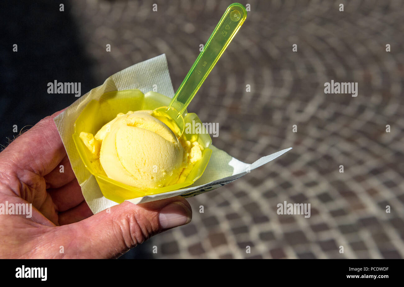 Kugel Zitrone Eis in einem Kunststoffbehälter mit Löffel. Stockfoto