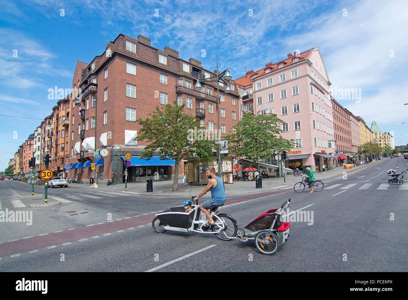 STOCKHOLM, Schweden - 11. JULI 2018: Radfahrer mit Kind wagen Kreuze Sankt Eriksplan in Vasastan am 11. Juli 2018 in Stockholm, Schweden. Stockfoto