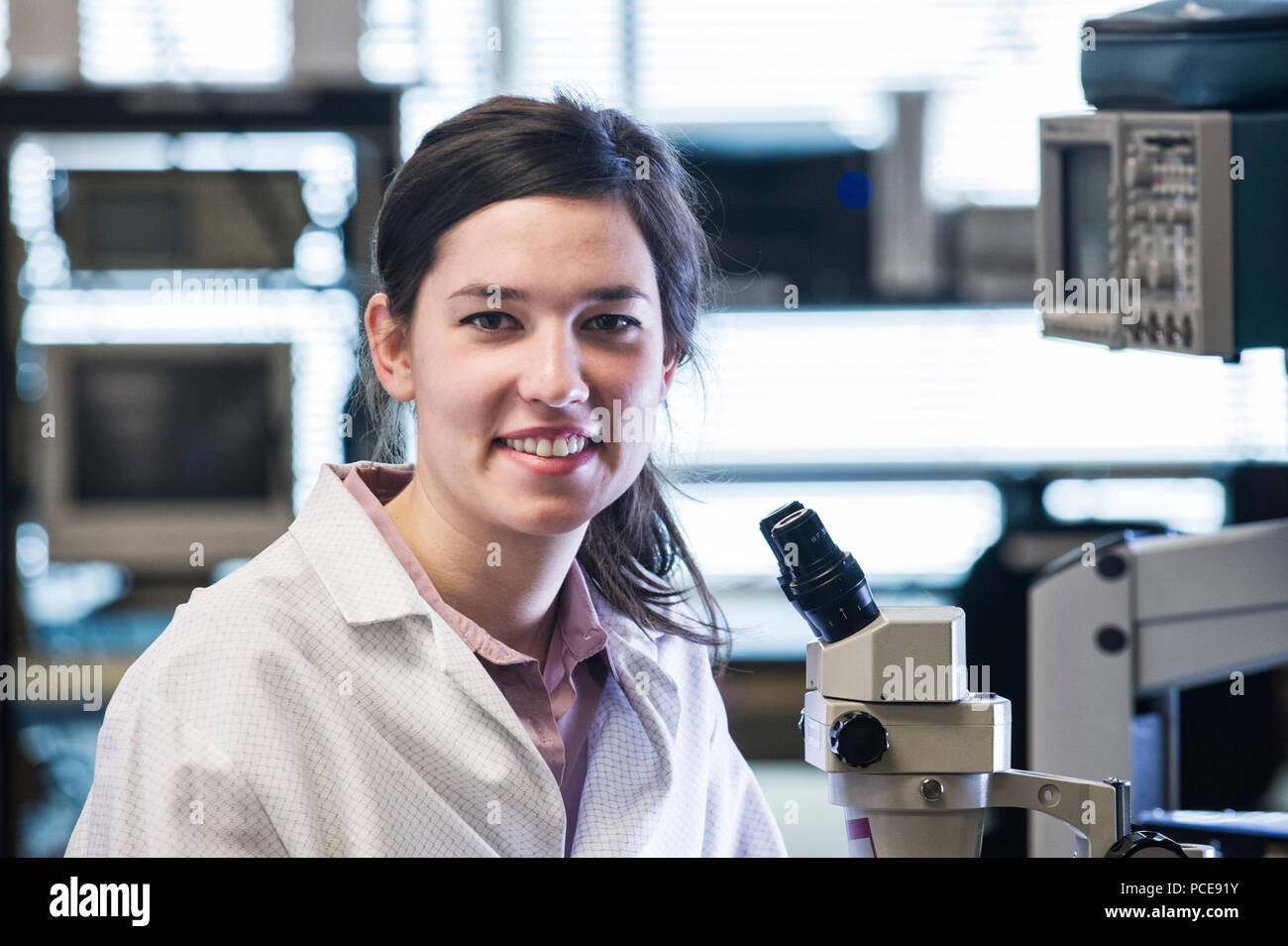 Das Porträt einer weiblichen techniciain an ein Mikroskop in der technischen Forschung und Entwicklung. Stockfoto