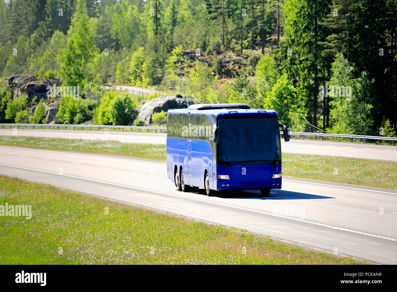 Bus blau Bus fährt unter Autobahn Auto Verkehr an einem sonnigen Tag im Sommer. Stockfoto