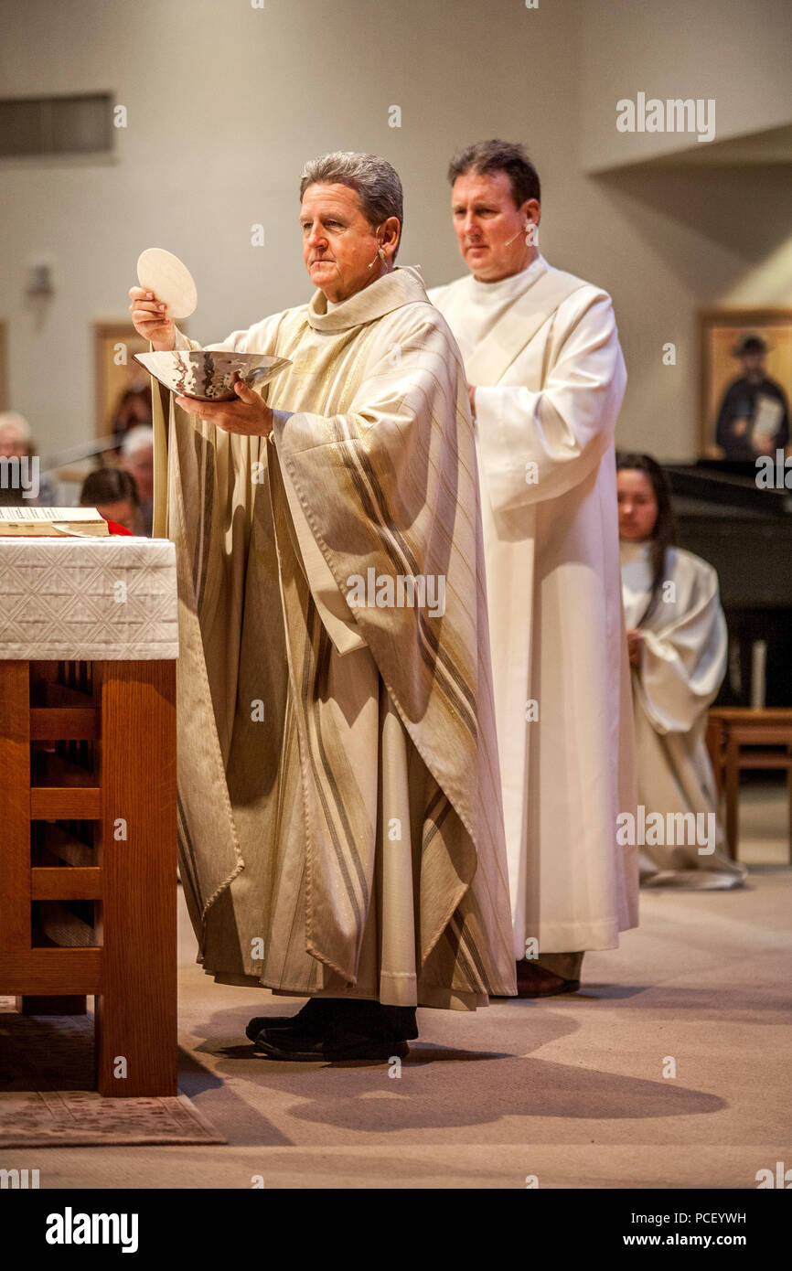 Ein Robed Diakon beteiligt sich in der Gemeinschaft bei einer Masse von einem monsignore an einem Laguna Niguel, CA, Katholische Kirche durchgeführt. Hinweis heilige Wafer. Stockfoto