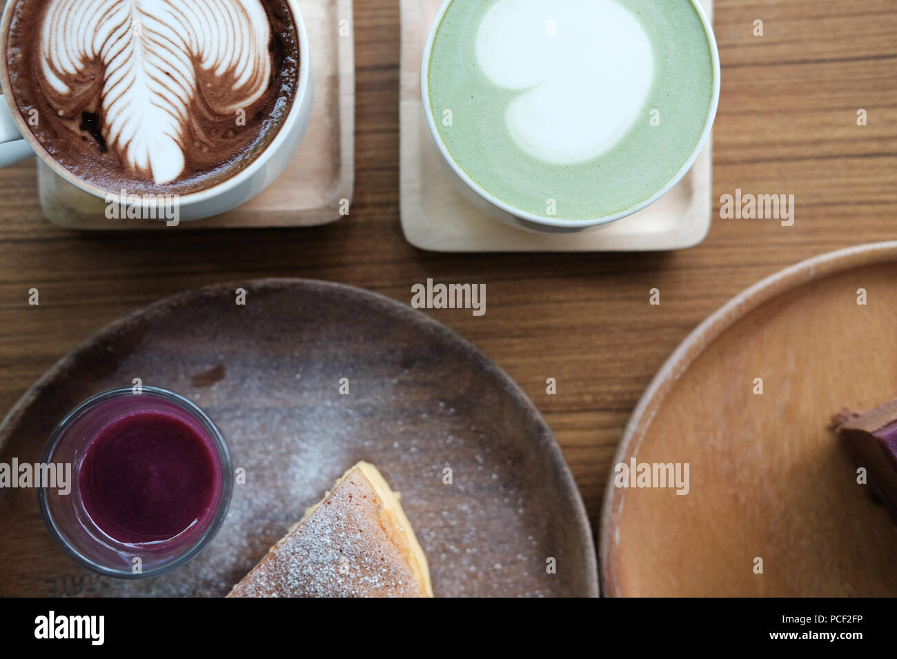 Hot Matcha Grüntee mit Herz latte Art Käsekuchen mit Beeren Soße auf Holz Fach Stockfoto