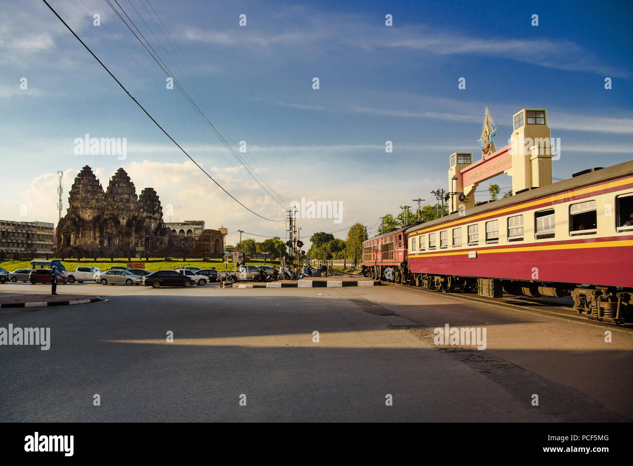 Der Zug überquert die Straße am dem 13. Jahrhundert Phra Prang Sam Sie Tempel in Lopburi Provinz, Thailand. Stockfoto
