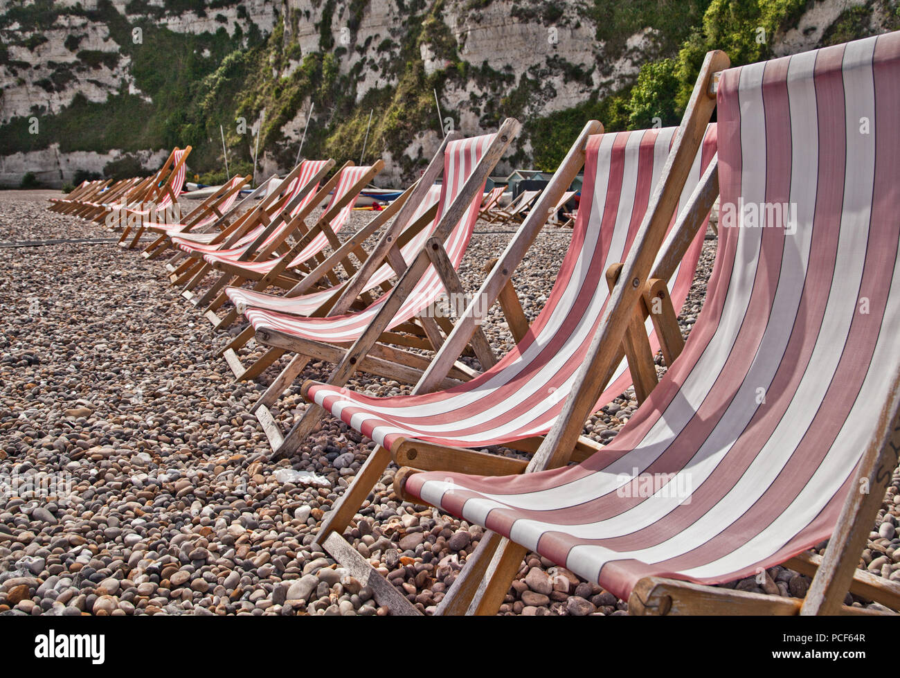 Rote Liegestühle auf einem Kieselstrand Stockfoto