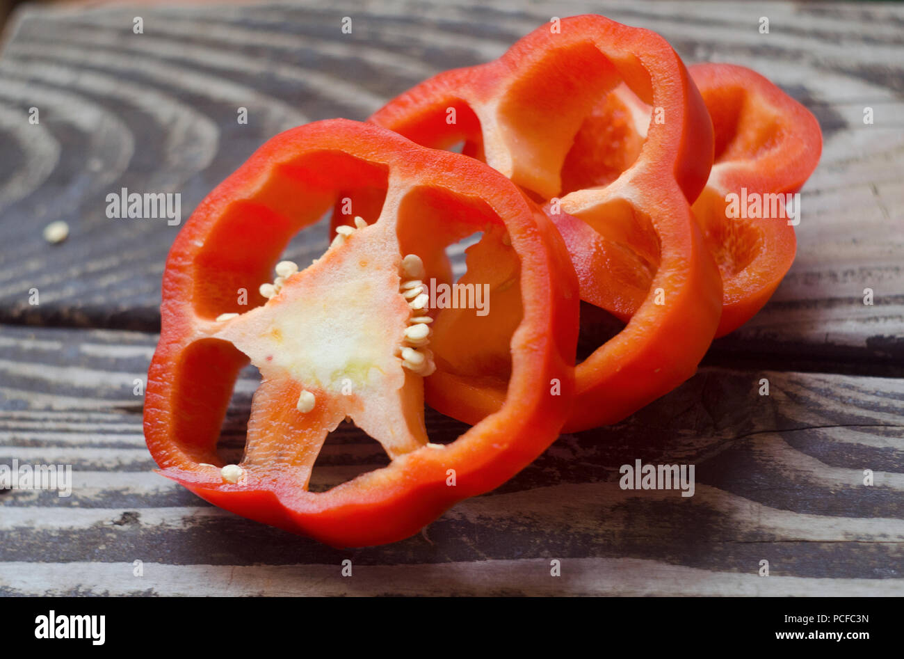 In Scheiben geschnittene Paprika auf hölzernen strukturierten Hintergrund isoliert. Essen Hintergrund. Bunte rote gehackt Pfeffer auf rustikalen Holztisch. Stockfoto
