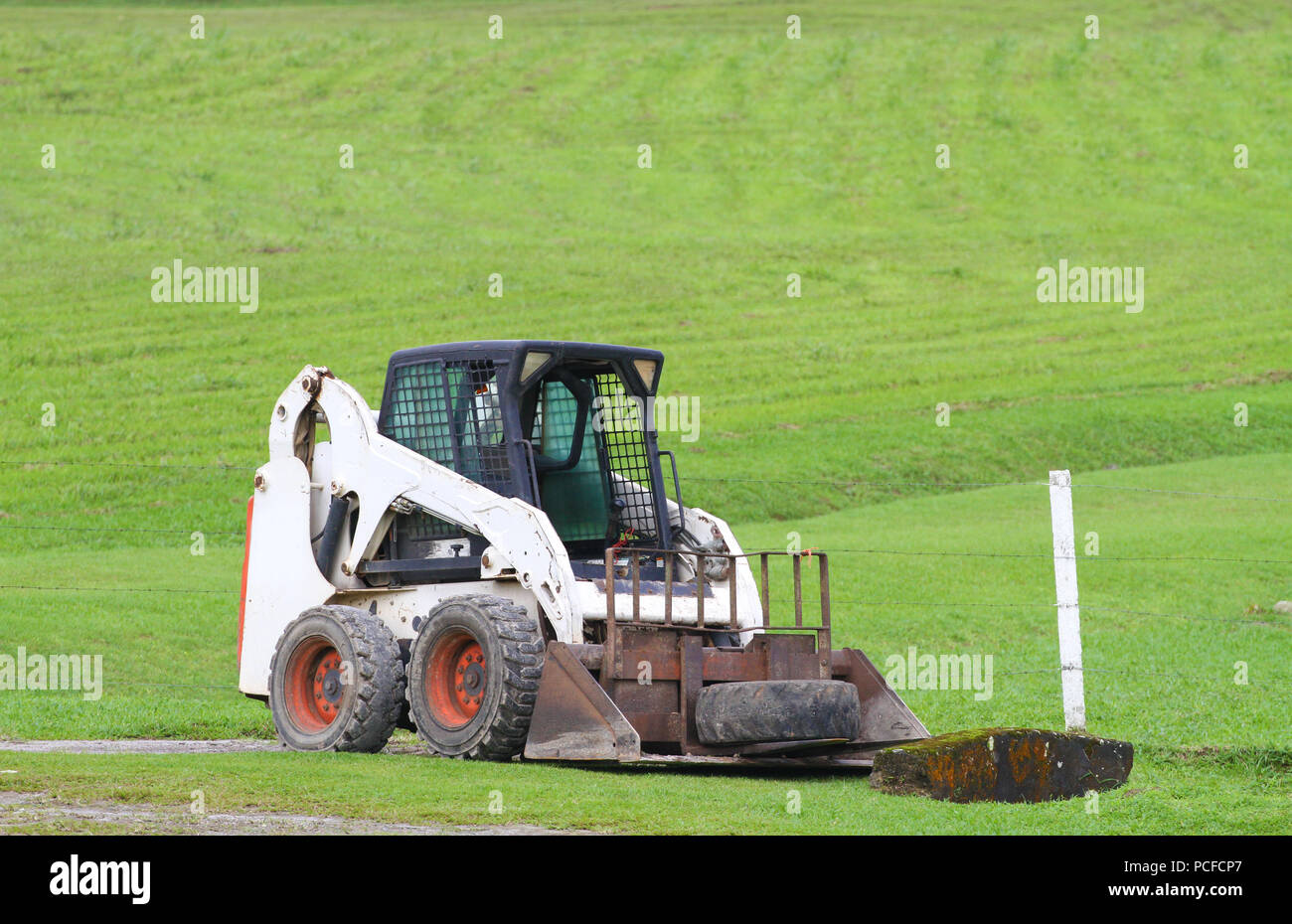 Alte Kompaktlader auf ein Feld Betrieb geparkt wartet Arbeit zu beginnen Stockfoto