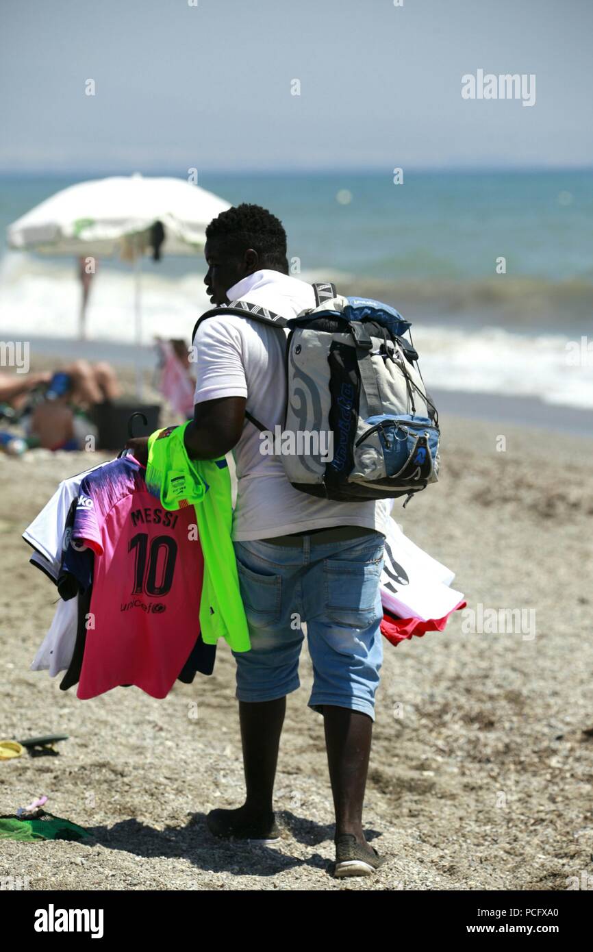 Roquetas de Mar, Almeria, Spanien. 2 Aug, 2018. Die Hitzewelle, schlägt Spanien wird erwartet, 43°C in einigen Teilen des Landes zu überschreiten. Mann verkauf Strand Artikel, t-shirts zu Fuß entlang der Strandpromenade. Foto: Paul Lawrenson/Alamy leben Nachrichten Stockfoto