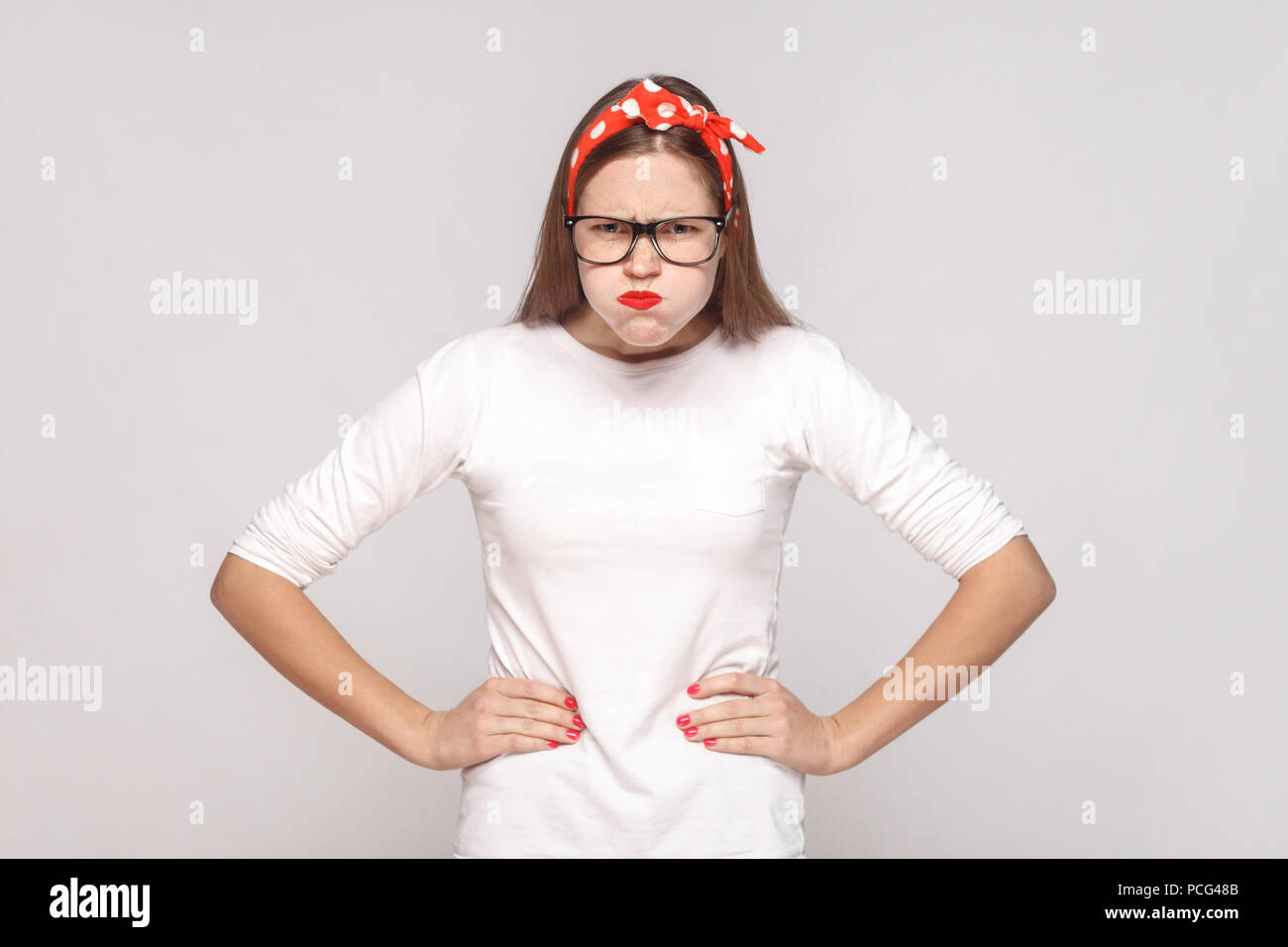 Wütend thinkful, hob die Hände. Porträt der Schönen emotionalen junge Frau im weißen T-Shirt mit Sommersprossen, schwarze Brille, rote Lippen und Kopfband. Pflege Stockfoto