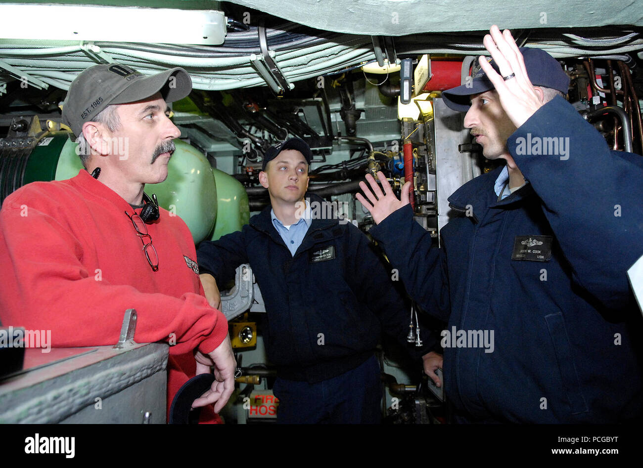Petty Officer 1st Class Jason Cook, Maschinist, Kumpel, und Petty Officer 2nd class Mark Cygnarowicz, machinist mate, zugeordnet zu den schnell Angriffs-U-Boot USS Alexandria (SSN 757) Der sub Waffen Systeme erklären zu Country Music Star Aaron Tippin. Tippin tourte das U-Boot vor der Durchführung ein kostenloses Konzert in der Naval Submarine Base New London als Teil der Geist von Amerika Tour. Stockfoto