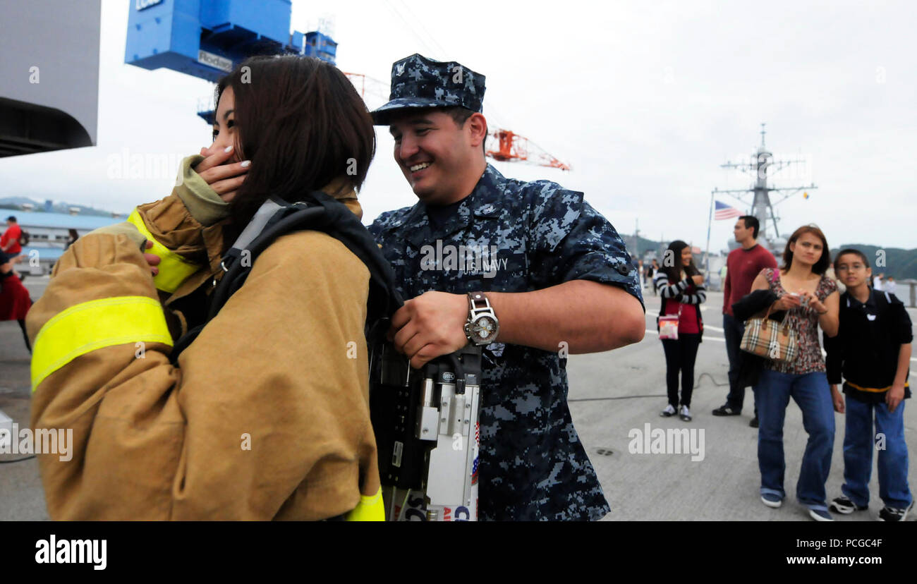 Petty Officer 3. Klasse David Hyndman, machinist mate, hilft ein Gast an Bord des US-amerikanischen 7 Flotte Befehl Schiff USS Blue Ridge Kleid in eine Brandbekämpfung Ensemble, wie das Schiff unterwegs für eine Kreuzfahrt nach Tokio geht. Freunde und Familie von Blue Ridge und US 7 Flotte personal Matrosen, sowie Seeleute aus dem Japan Maritime Verteidigung-kraft waren an Bord für die 4-Stunde im Gange, der Empfohlene damage control Ausrüstung Demonstrationen und eine Leistung durch die USA 7 Flotte Band eingeladen. Stockfoto