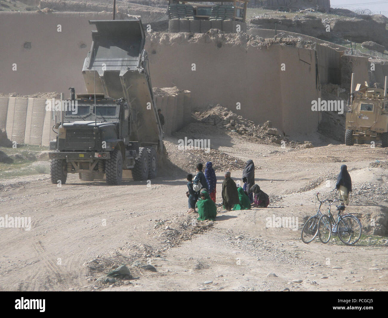 Afghanistan Kinder beobachten als Seabees vom Naval Mobile Bau-Bataillon 3 Ablösung Badger Dump Schmutz auf einer Straße, die sie sanieren sind. Die Seabees und Segler bei Ablösung Badger kehrte nach Camp Leatherneck, April 6, nachdem er mehr als 70 Tage unter rauen Bedingungen leben, wie sie zwei Basen gebaut und eine Straße in der Nähe von afghanischen Sangin Distrikt renoviert. NMCB 3 ist ein Expeditionskorps Element der US Naval Forces Bereitstellung, Bau, Technik und Sicherheitsdienstleistungen zur Unterstützung der nationalen Strategie, Marineenergie Projektion, humanitäre Hilfe und Kontingenz Betriebs- Stockfoto