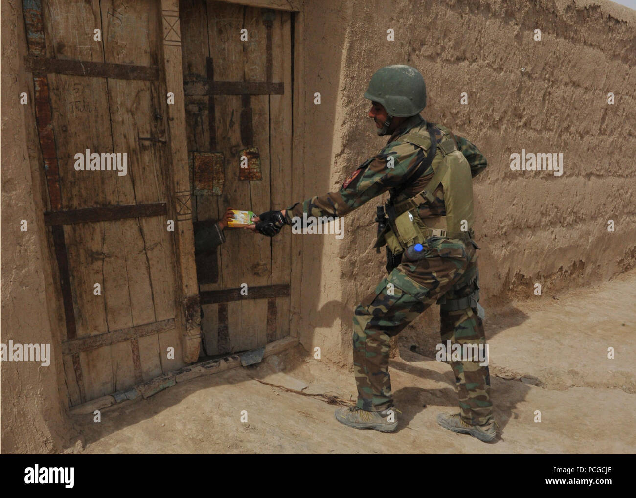 Ein Afghan National Army Special Forces Soldat Hände ein Saft, um einen Jungen aus Afghanistan bei demontiertem Patrouille in Latif Bezirk, Provinz Ghazni, Afghanistan, am 31. März. Demontiert Patrouillen werden verwendet, um lokale Afghanen zu engagieren und eine Beziehung mit führenden Persönlichkeiten im Bereich entwickeln. Stockfoto