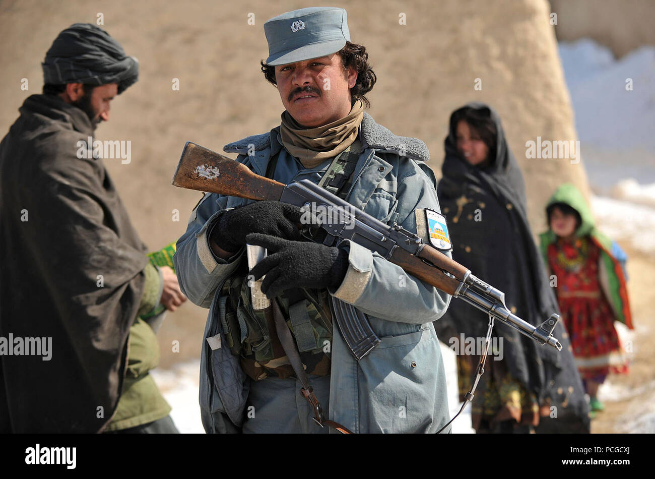 Eine nationale afghanische Polizei Mitglied liefert Sicherheit, während andere Mitglieder essen und kaltem Wetter Kleidung in Molla Owrang Dorf verteilen, Nawbahar Bezirk, Zabul Province, Afghanistan, Feb 7. Die Produkte unterstützen die Dorfbewohner durch den harten Winter. Stockfoto