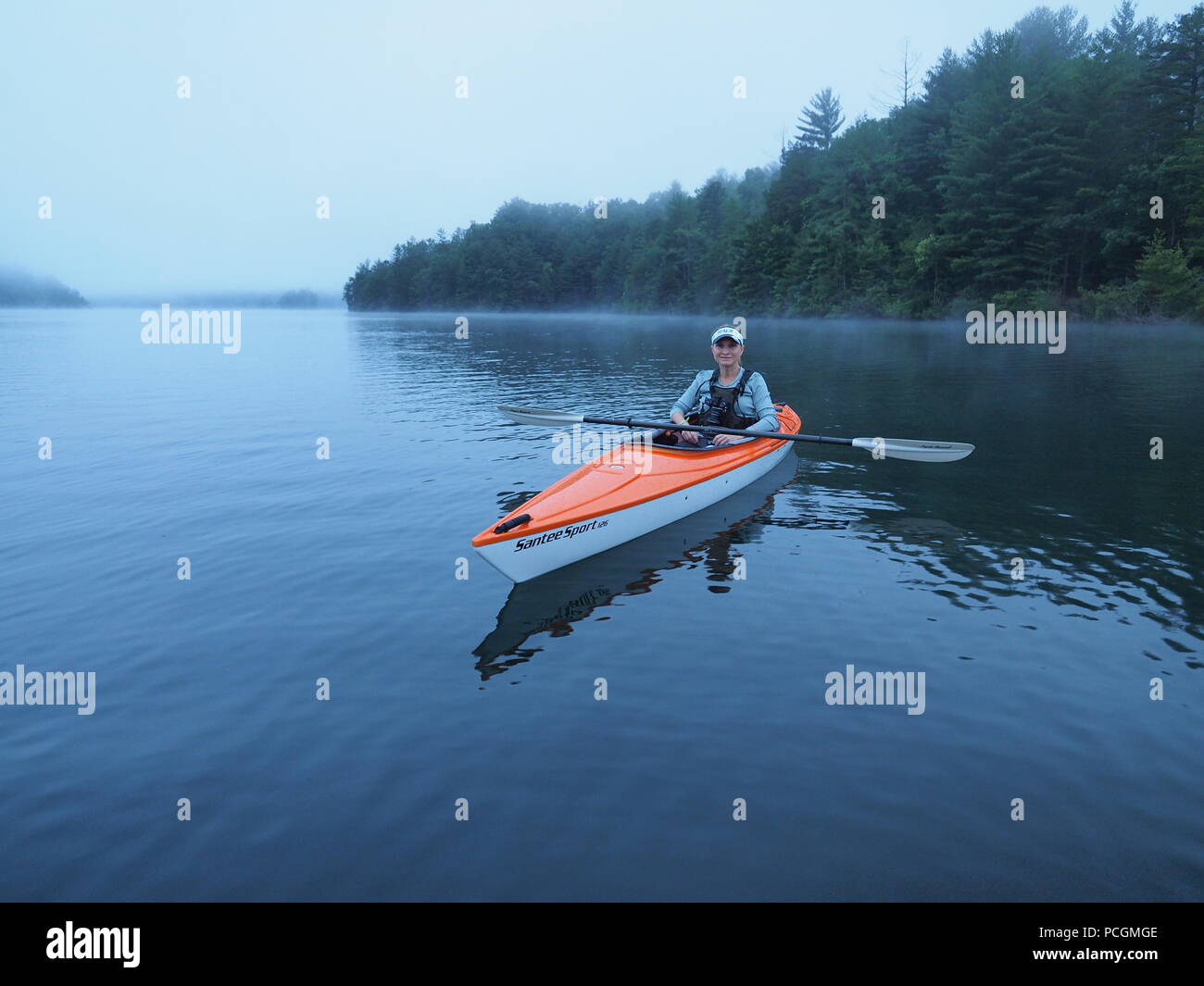 Frau Kajakfahren auf dem See Santeetlah, North Carolina, United States an einem nebligen Morgen. Stockfoto