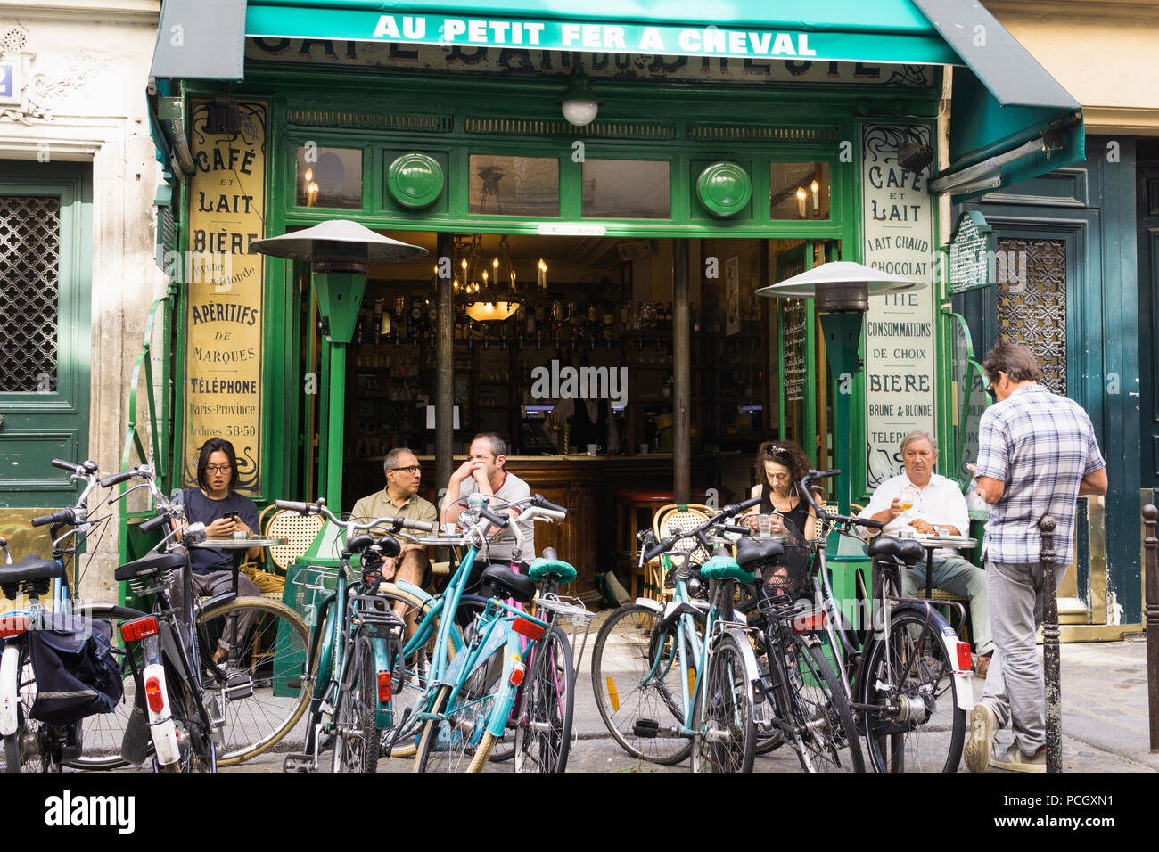 Paris Cafe Au Petit Fer a Cheval-Gönner mit morgendlichem Kaffee im Cafe Au Petit Fer a Cheval mit Fahrrädern vor geparkt, Frankreich, Europa. Stockfoto